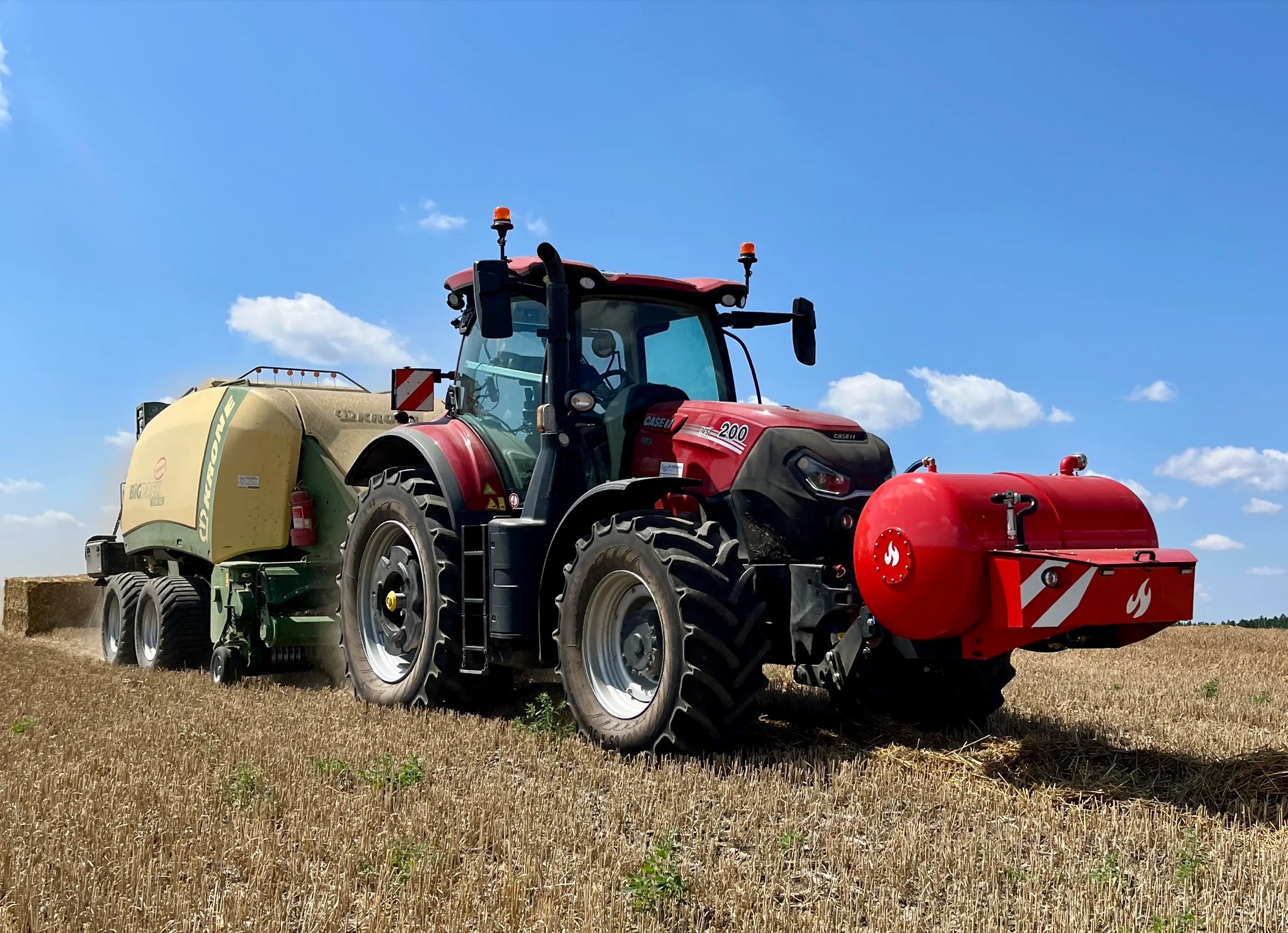 Traktor Case IH s HYDROTANKEM a lisem Krone při lisování slámy na poli