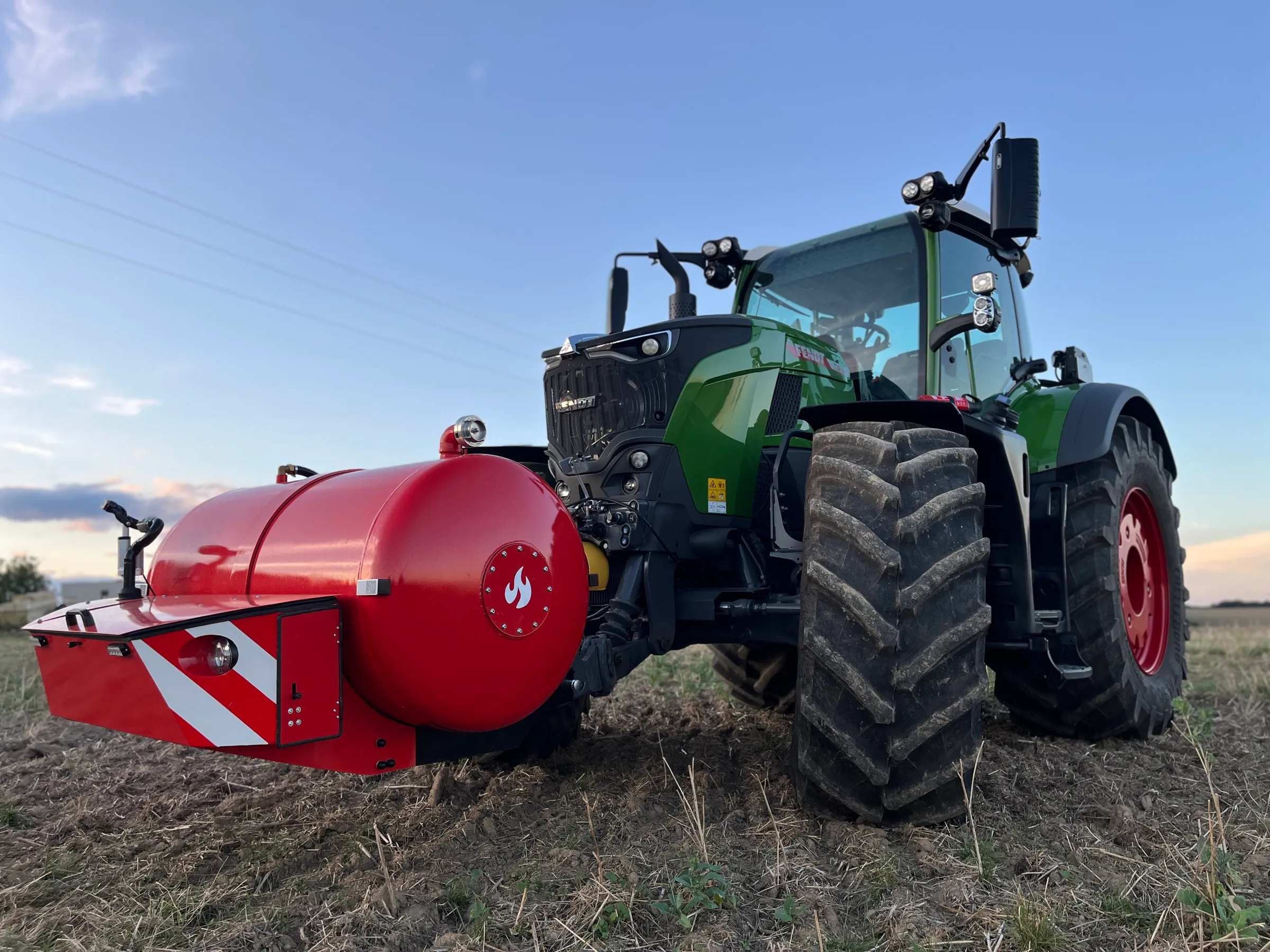 Traktor Fendt s nádrží HYDROTANK na čelním závěsu na podvečerním strništi