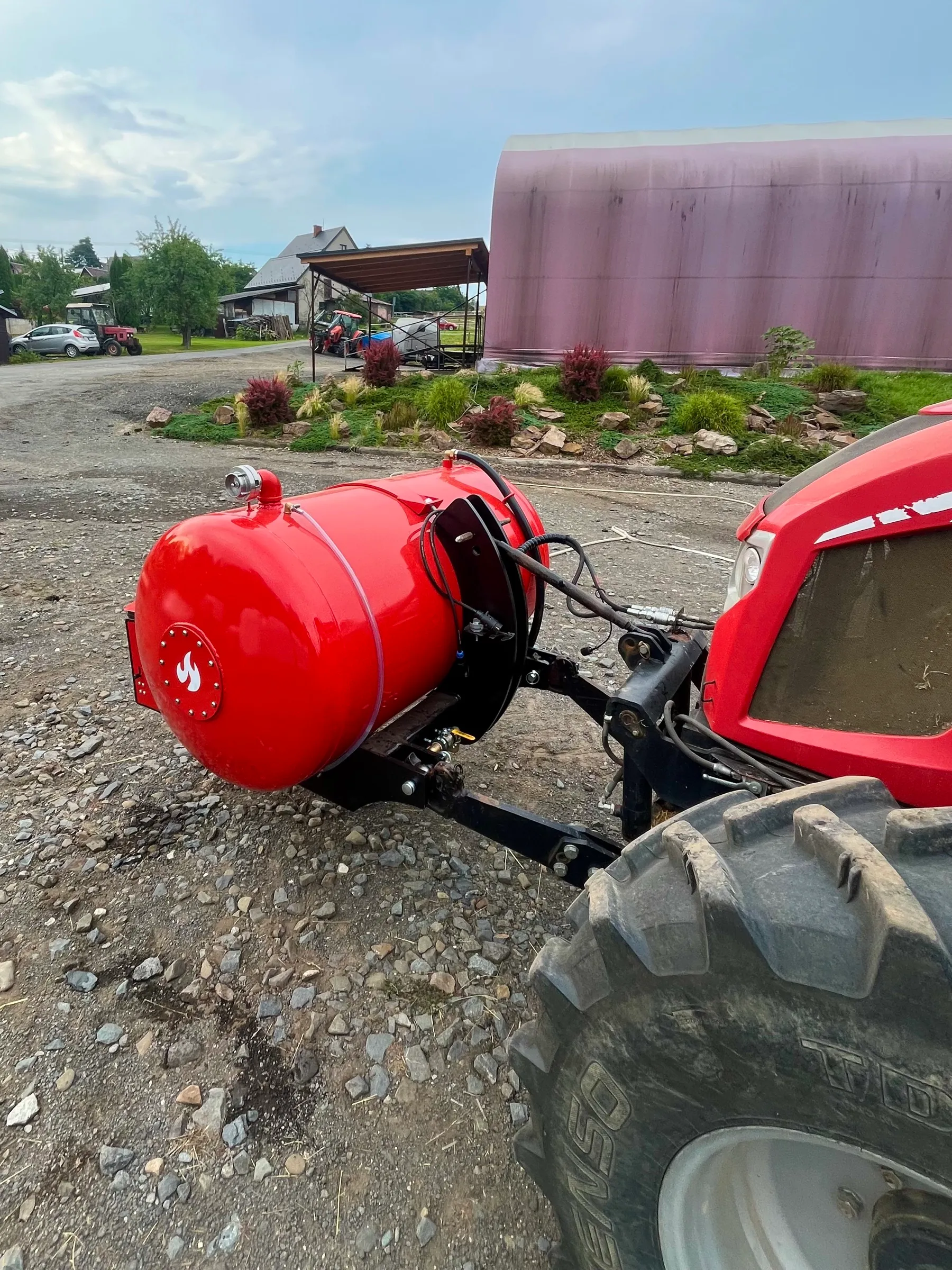 Nádrž HYDROTANK nasazená na čelním závěsu menšího traktoru na dvoře farmy